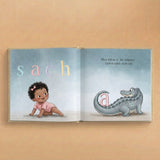 Open personalized book with illustration of a child and alligator on a beige background